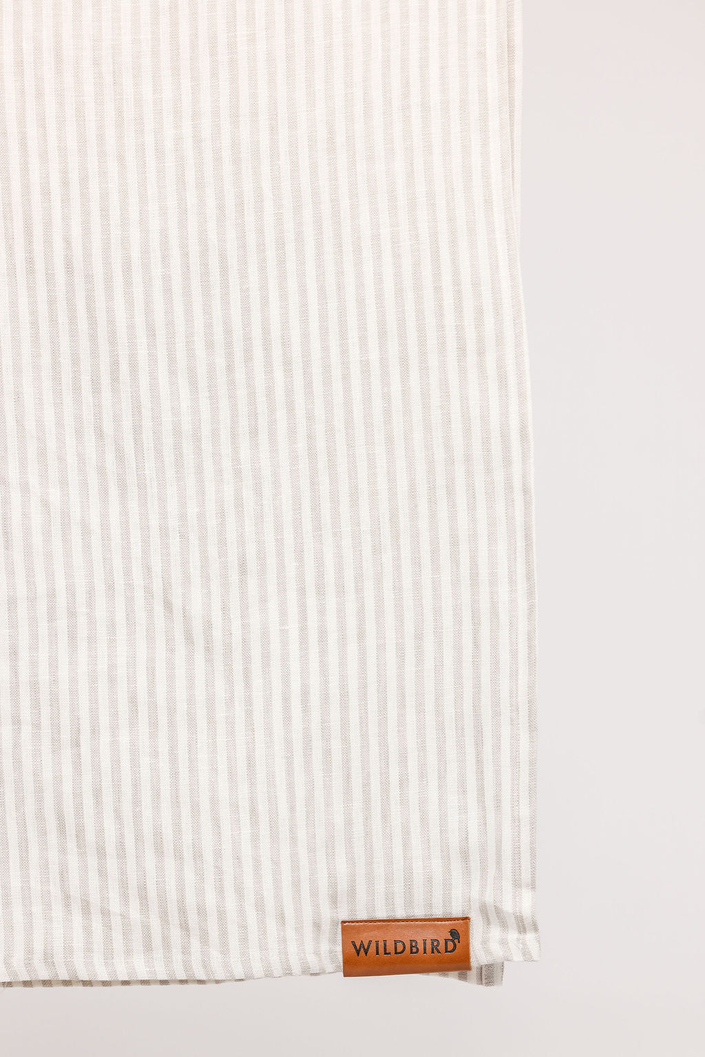 Textured white fabric with a leather tag labeled 'Wildbird' on a light gray background