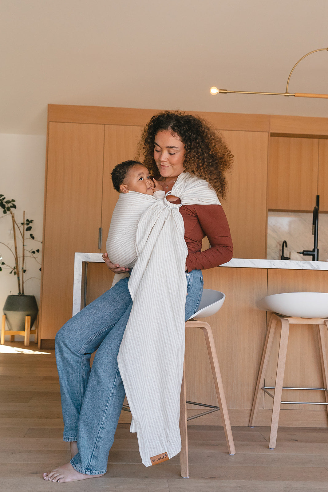 Woman holding a baby in a sling in a kitchen setting